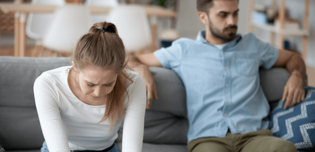 Unhappy young millennial married couple sitting on couch in living room after quarrel fight.